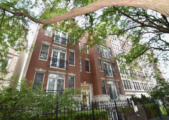 Front view of a multi-story brick building with large windows and decorative balconies.