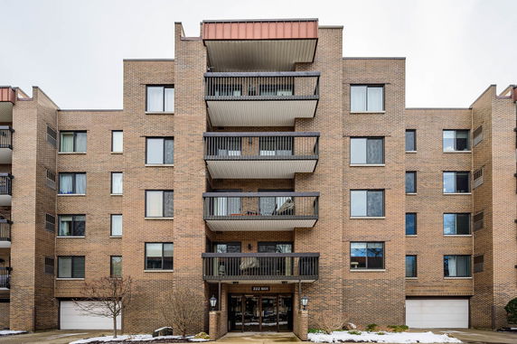 Front view of a multi-story brick apartment building with balconies.