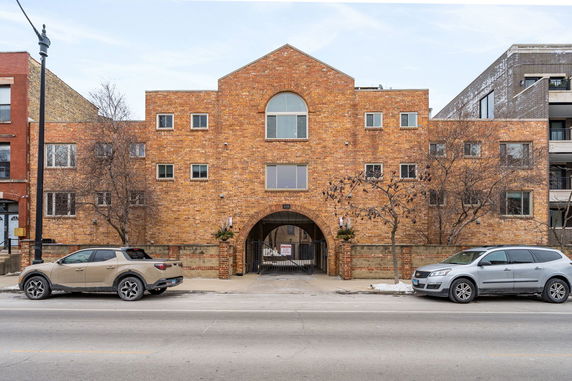 Front view of a brick multi-story residential building with a central archway entrance.