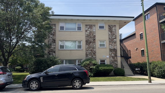 Front view of a two-story apartment building with brick and stone facade.