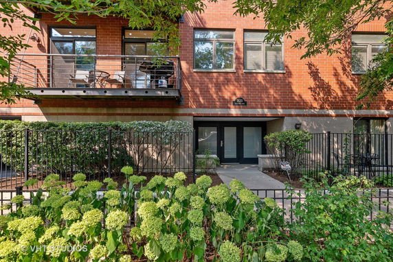 Front view of a multi-story brick building with a balcony and gated entry.
