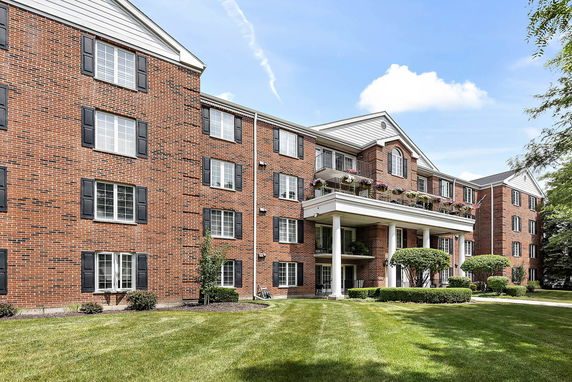 Front view of a multi-story brick building with balconies and large windows.