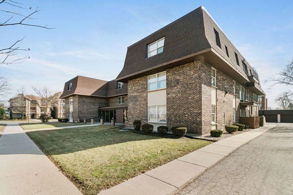 Front view of a residential building with a brown brick facade and sloped roof.
