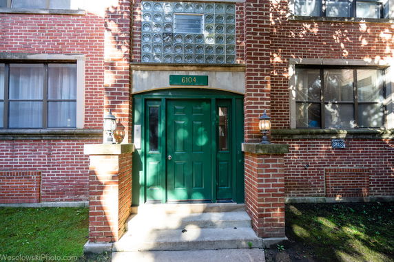 Front view of a brick building entrance with a green door and glass block window.