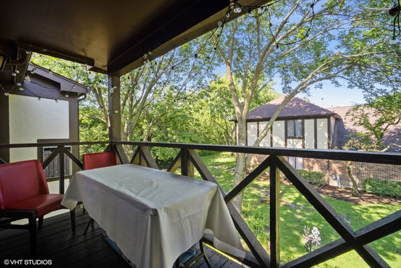 View from a covered balcony showcasing surrounding greenery and adjacent buildings.