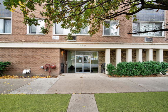 Front view of a brick building with multiple windows and an entrance canopy.