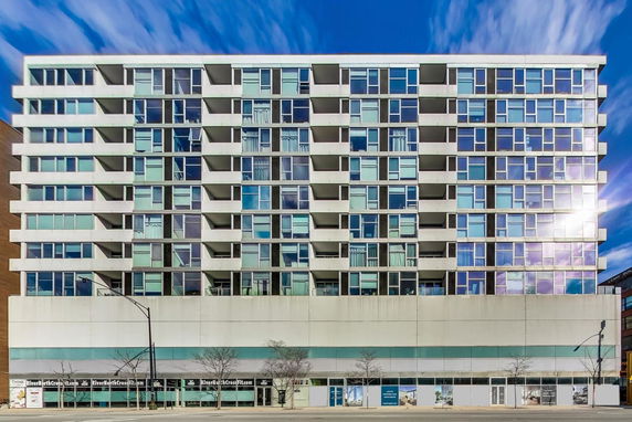 Front view of a modern multi-story residential building with balconies and large windows.