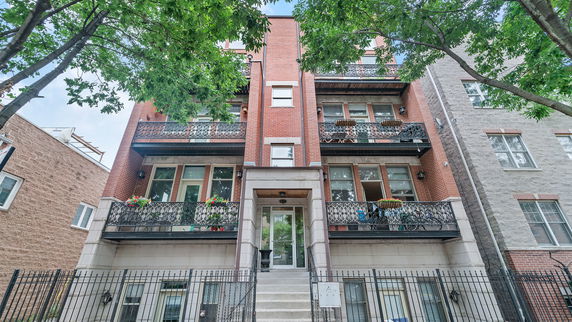 Front view of a multi-story brick apartment building with balconies.