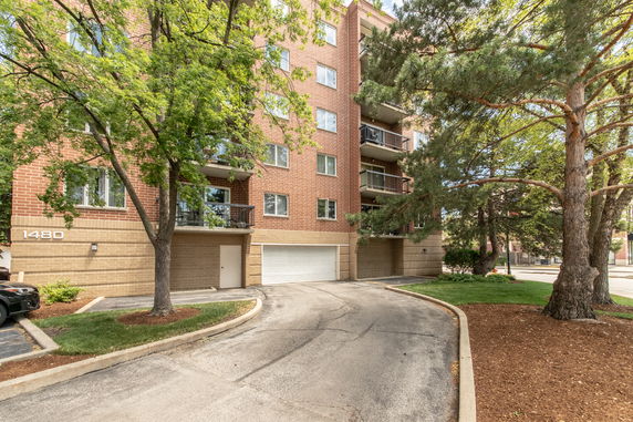 Front view of a multi-story brick building with balconies and a garage entrance.