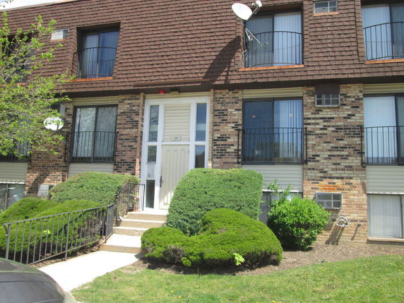 Front view of a multi-story building with a brick facade and a shingle roof.