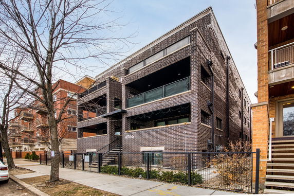 Front view of a modern multi-story building with brick exterior and balconies.