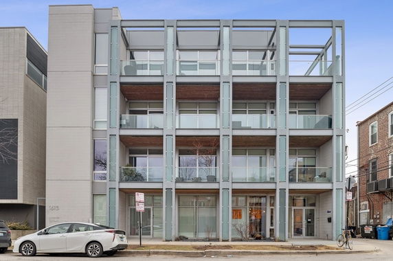 Front view of a modern multi-story building with large glass balconies.