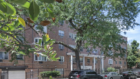 Front view of a multi-story brick apartment building with large windows.
