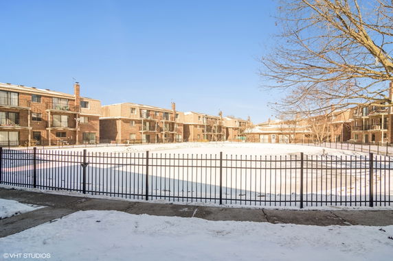 Outdoor view of a residential complex with surrounding fenced area and a covered swimming pool.