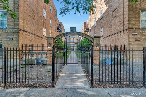 Front view of a brick apartment building with an arched entrance gate.