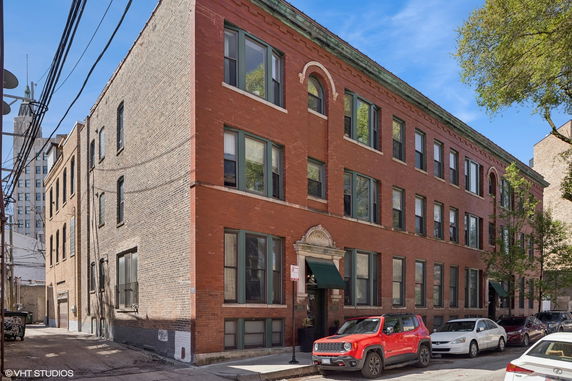 Front view of a multi-story red brick building with multiple windows and a decorative entrance.