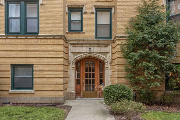 Front view of a brick building with decorative stone arch and wooden door.