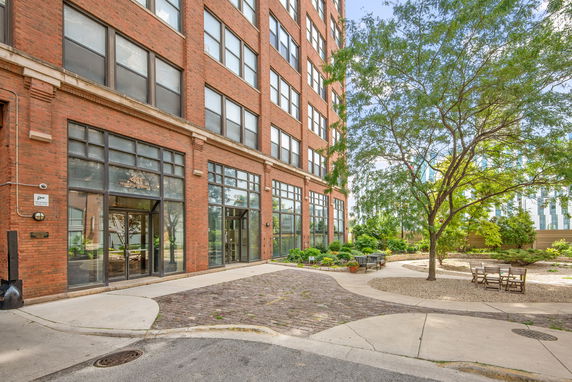 Front view of a multi-story brick building with large windows and a courtyard area.