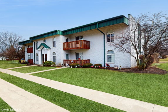 Front view of a two-story building with balconies and green roof accents.