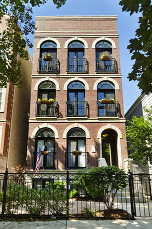 Front view of a multi-story brick building with arched windows and balcony railings.