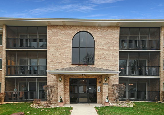 Front view of a three-story brick apartment building with balconies.