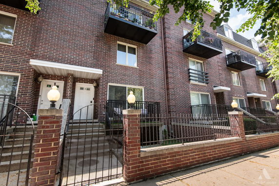 Front view of a multi-story brick building with balconies and staircase entrances.