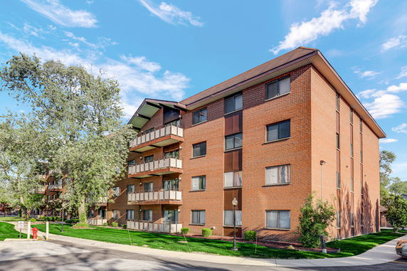 Front view of a multi-story brick apartment building with balconies.