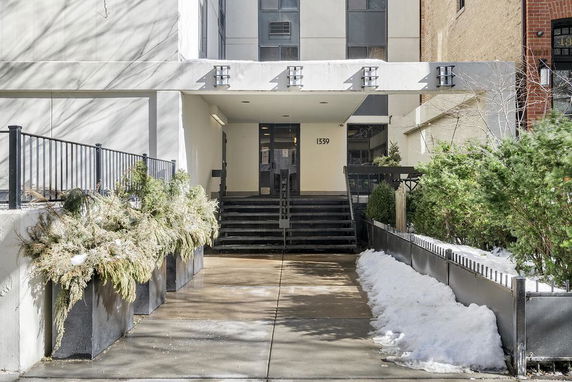 Front view of a residential building entrance with steps and railing.