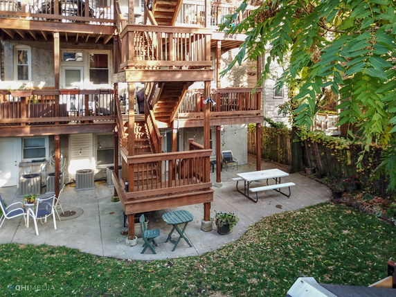 Back view of a multi-story building with wooden balconies and patio area.