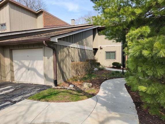 Front view of a house with a single garage door and sloped roof.