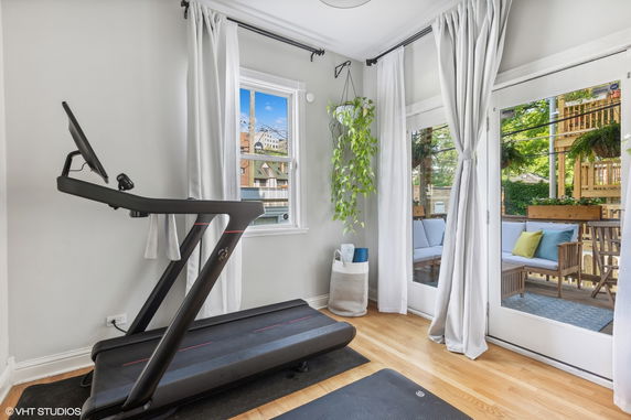Room with a treadmill and yoga accessories, featuring large windows and outdoor views.