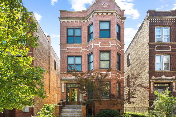 Front view of a three-story brick building with decorative patterns around windows.