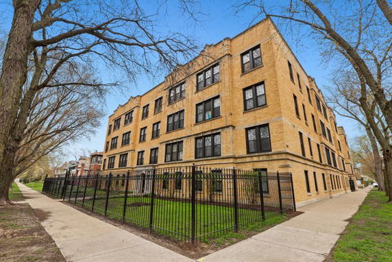 Front view of a multi-story brick apartment building with black railings.