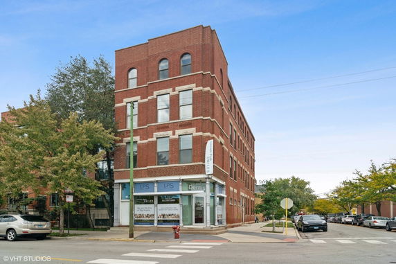 Front view of a multi-story brick building with commercial space on the ground floor.