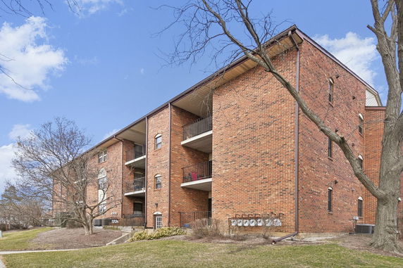 Front view of a multi-story brick apartment building with balconies.