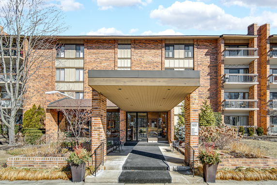 Front view of a multi-story brick building with balconies and a covered entrance.