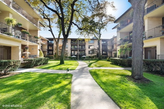 Front view of a multi-story apartment complex with balconies and landscaped paths.