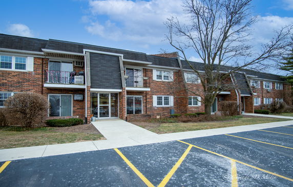 Front view of a two-story brick building with balconies and parking area.