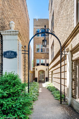 Front view of a multi-story brick building with an archway entrance and decorative lantern.