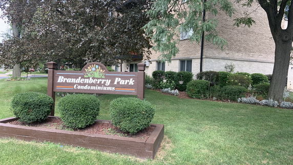 Front view of a condominium building with landscaping and signage.