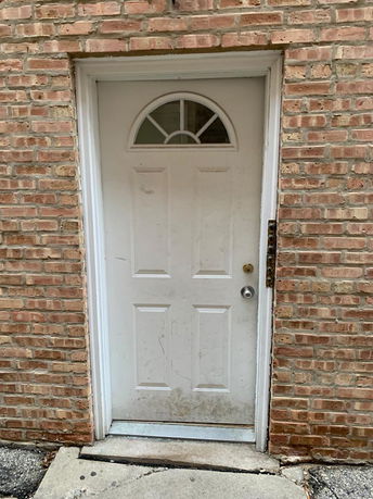 Front view of a white door set in a brick wall.