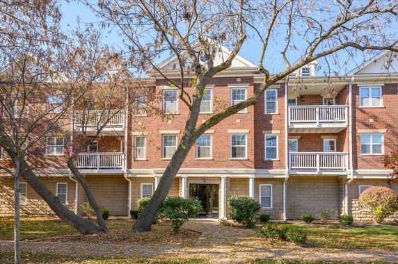 Front view of a multi-story brick apartment building with balconies.