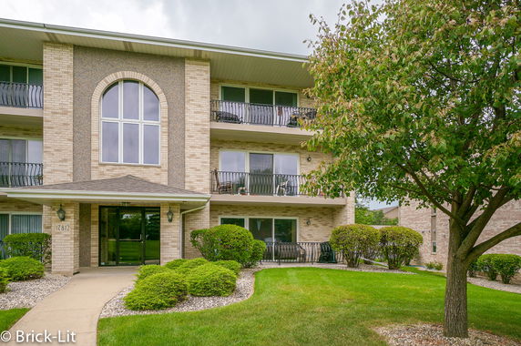 Front view of a three-story apartment building with balconies and a central entrance.
