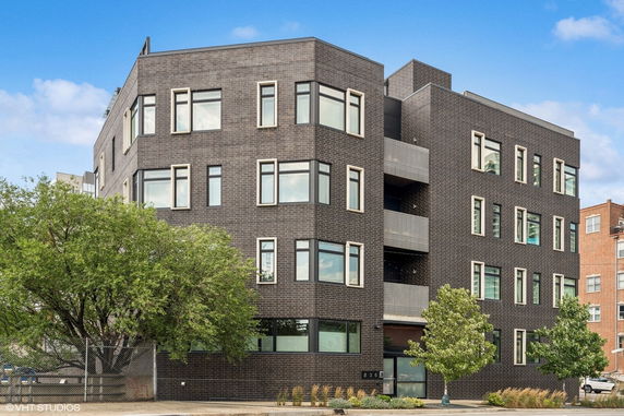 Front view of a modern multi-story building with dark brick facade and numerous windows.