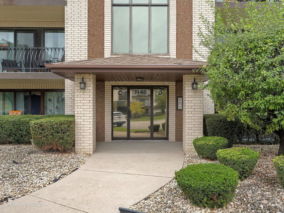 Front view of a multi-story building entrance with brick façade and glass doors.