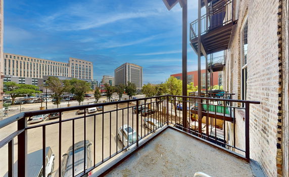 View from a balcony showing several buildings and a parking area.