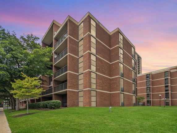 Front view of a multi-story brick building with balconies and large windows.