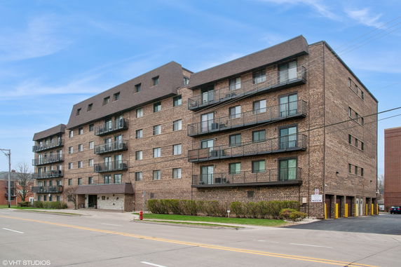 Front view of a multi-story brick apartment building with balconies.