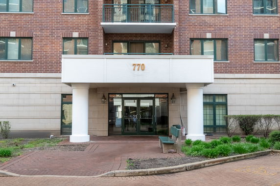 Front view of a multi-story building with a brick exterior, pillars, and glass entrance doors.