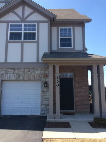 Front view of a two-story house with a garage and a covered entrance.